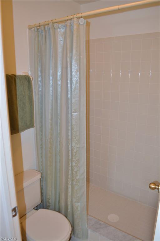 240 Timber Lake Circle, Unit D202 Naples, FL 34104 - Photo 15 of 23 a white toilet sitting next to a shower curtain