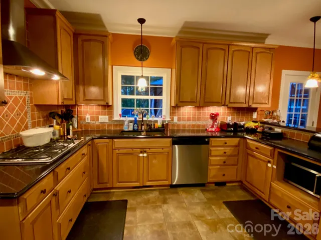 a kitchen with stainless steel appliances granite countertop a stove and wooden cabinets