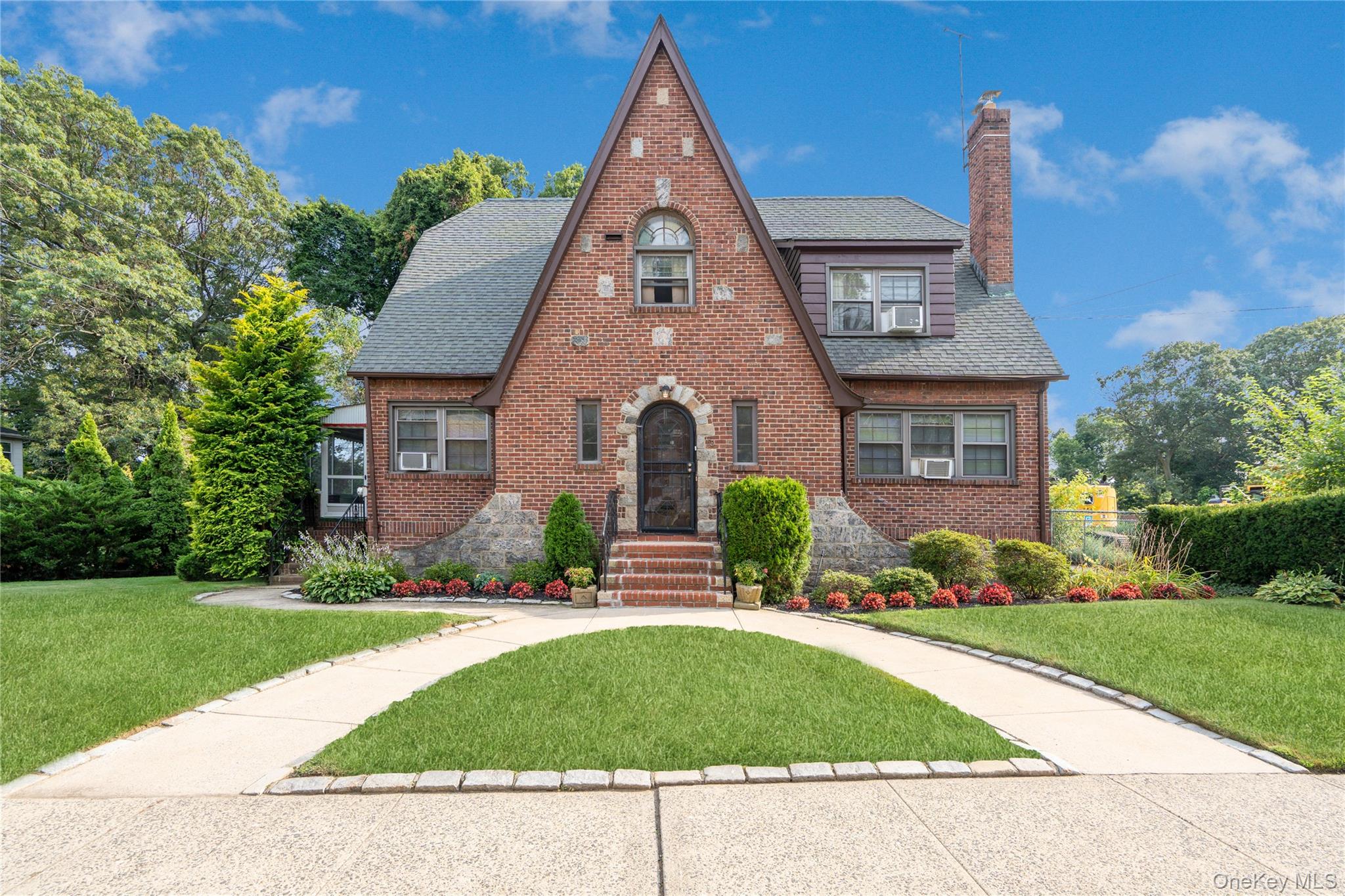 English style home with brick siding, a front yard, and roof with shingles