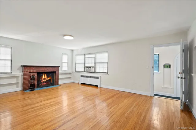 an empty room with wooden floor fireplace and windows