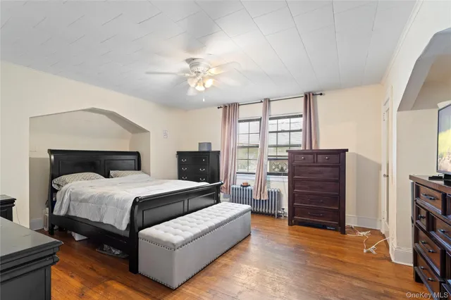 a spacious bedroom with a bed a dresser and a chandelier
