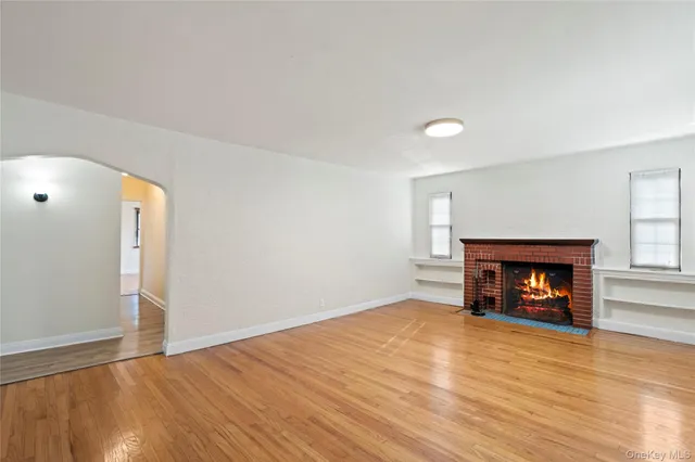 an empty room with wooden floor fireplace and windows