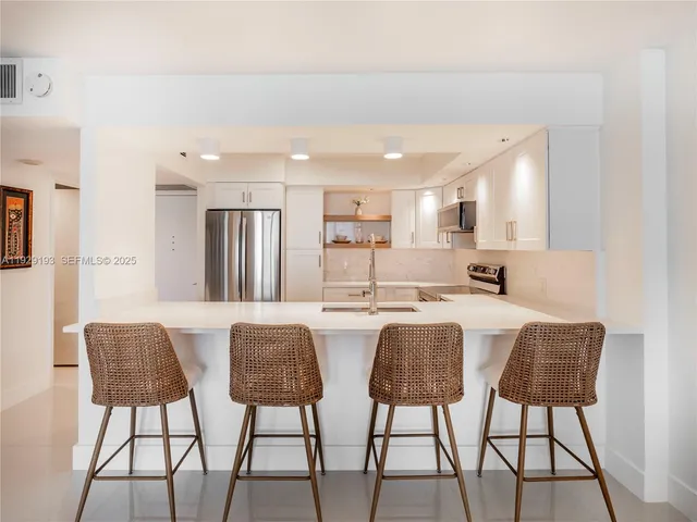 a kitchen with stainless steel appliances a dining table chairs and view living room