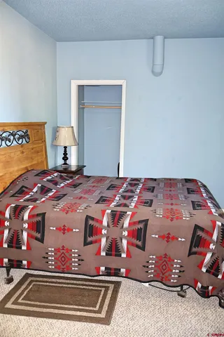 a bedroom with a bed and a lamp on dresser