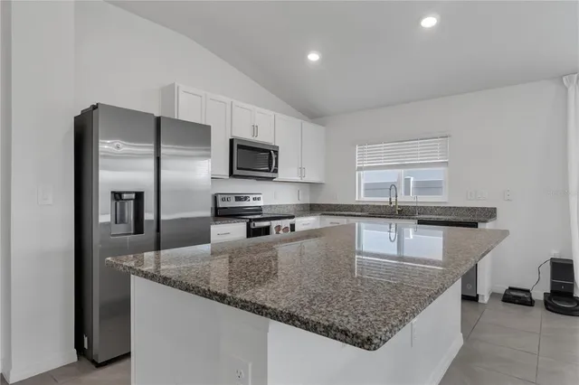 a kitchen with granite countertop a sink a counter top space cabinets stainless steel appliances and a counter top space