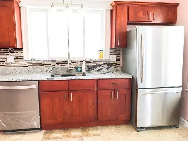 a kitchen with stainless steel appliances granite countertop a refrigerator and a sink