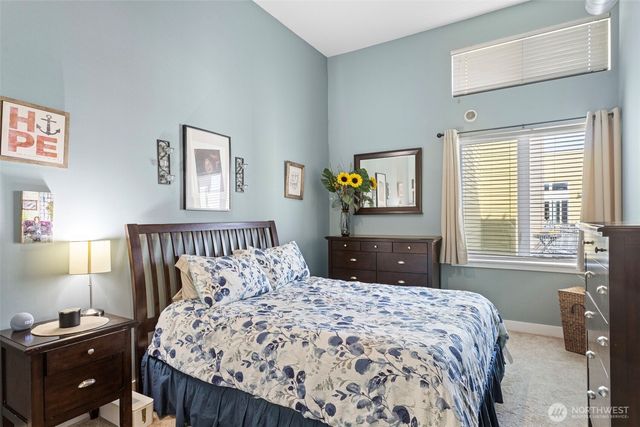 a bedroom with a large bed and a lamp on dresser