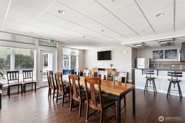 a kitchen with stainless steel appliances granite countertop a stove top oven a sink a dining table and chairs with wooden floor