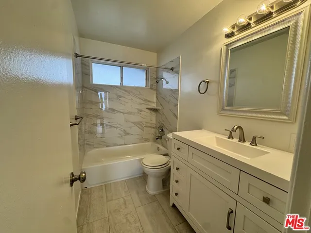 a bathroom with a granite countertop toilet a sink and a mirror