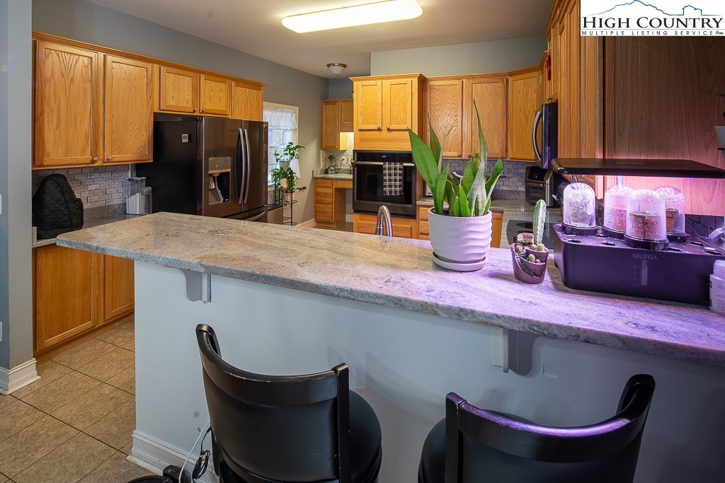 778 Roby Poe Road Crumpler, NC 28617 - Photo 14 of 50 a kitchen with stainless steel appliances granite countertop a sink refrigerator and microwave