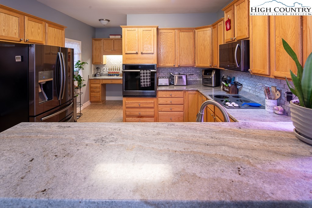 778 Roby Poe Road Crumpler, NC 28617 - Photo 15 of 50 a kitchen with stainless steel appliances granite countertop a stove a sink and a microwave
