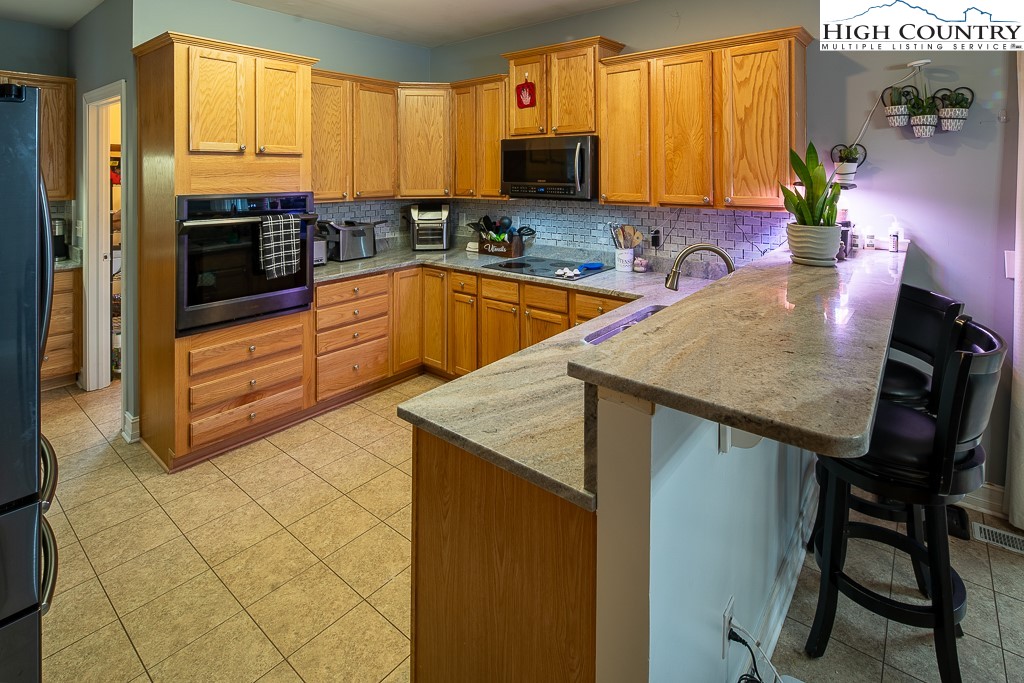 778 Roby Poe Road Crumpler, NC 28617 - Photo 16 of 50 a kitchen with stainless steel appliances a stove a sink a microwave a dining table and chairs with wooden floor