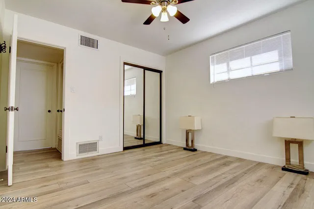 a view of empty room with wooden floor and fan