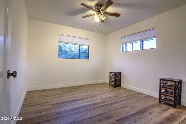 a view of an empty room with a window and wooden floor