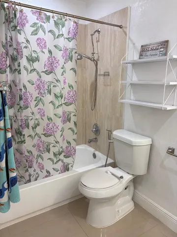 a white toilet sitting next to a shower curtain