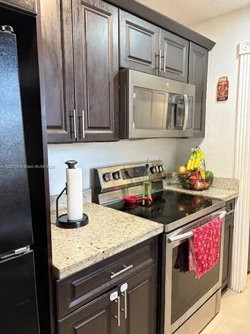 a kitchen with granite countertop stainless steel appliances stove top oven and cabinets