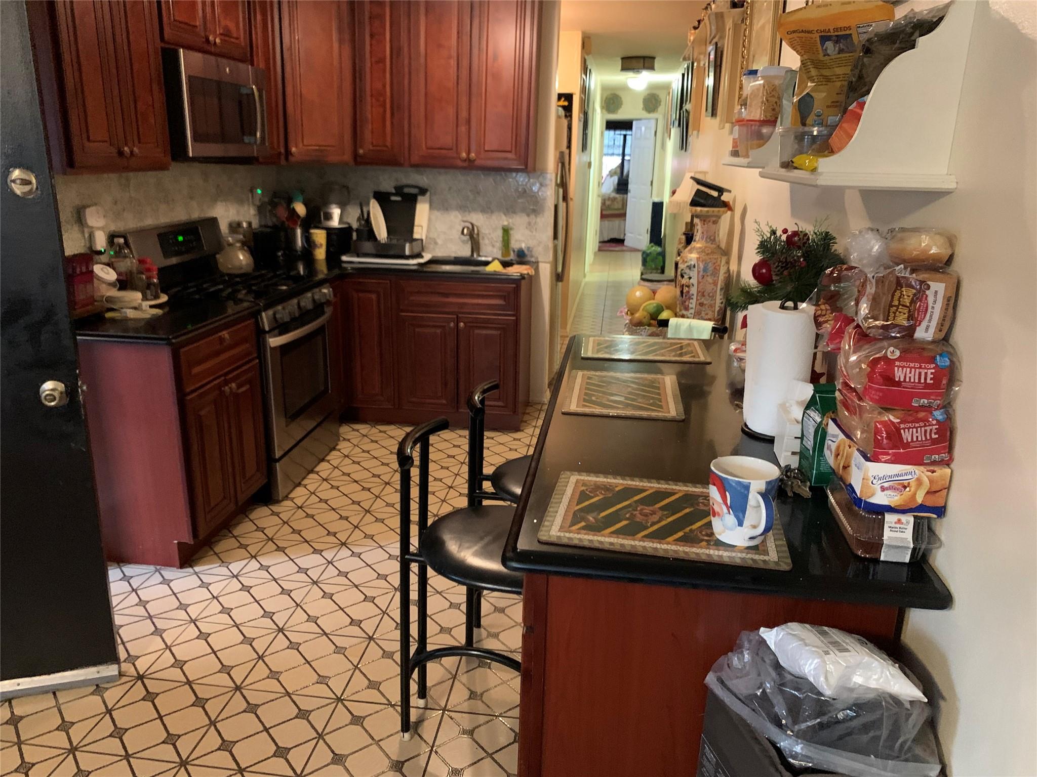 87-33 Commonwealth Boulevard Queens, NY 11426 - Photo 19 of 28 a kitchen with wooden cabinets and appliances