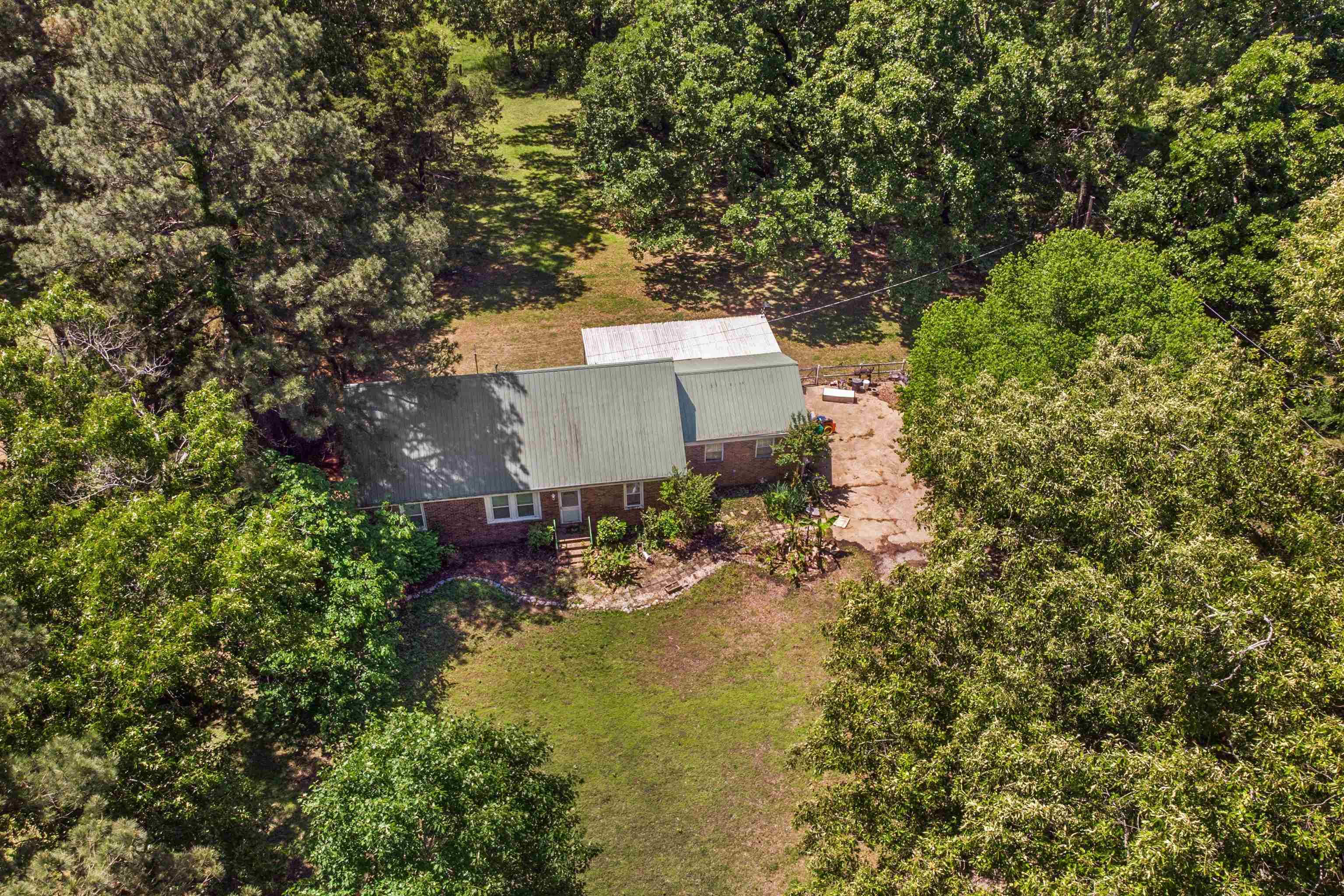 1147 North Collierville Arlington Road Collierville, TN 38017 - Photo 12 of 17 Brick residence featuring a green metal roof, a covered entry, and surrounding mature trees