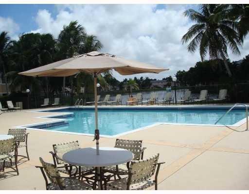 301 Palm Way, Unit 107 Pembroke Pines, FL 33025 - Photo 33 of 36 a patio with a table and chairs under an umbrella