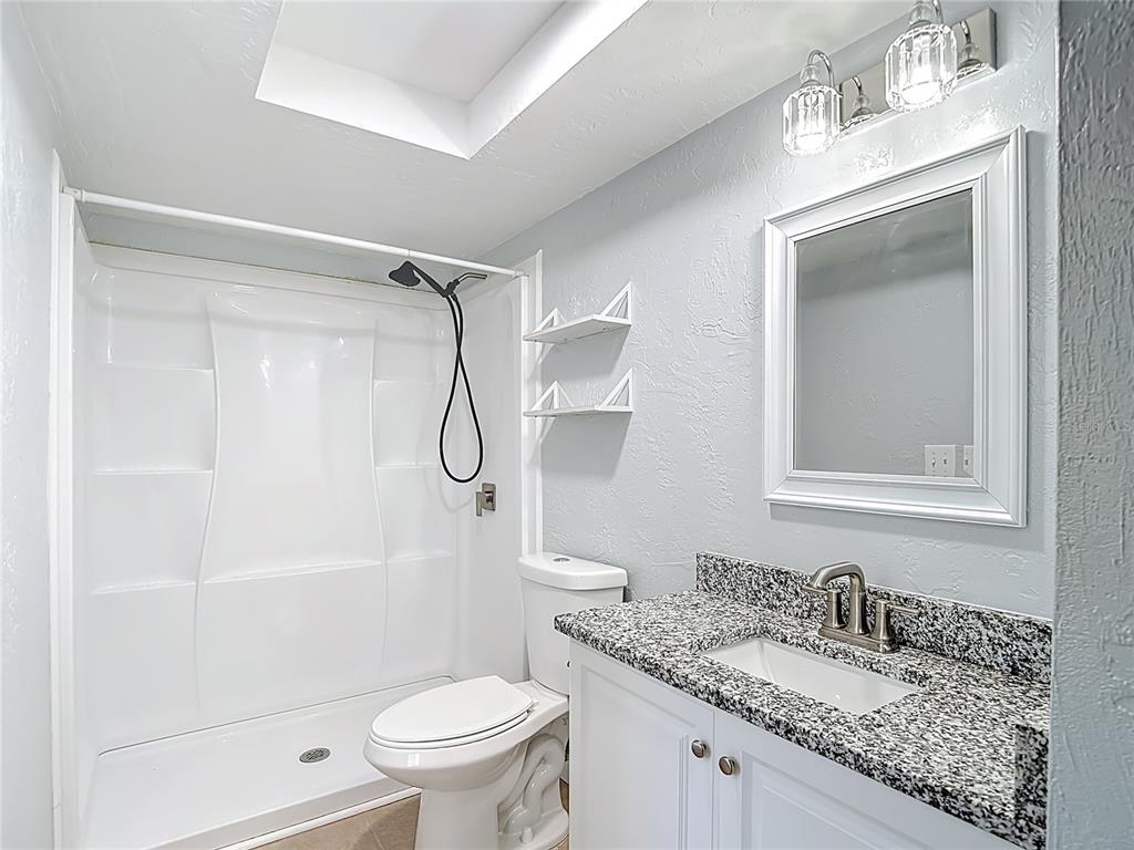 13156 Odham Street Spring Hill, FL 34609 - Photo 18 of 54 a bathroom with a granite countertop sink toilet and shower