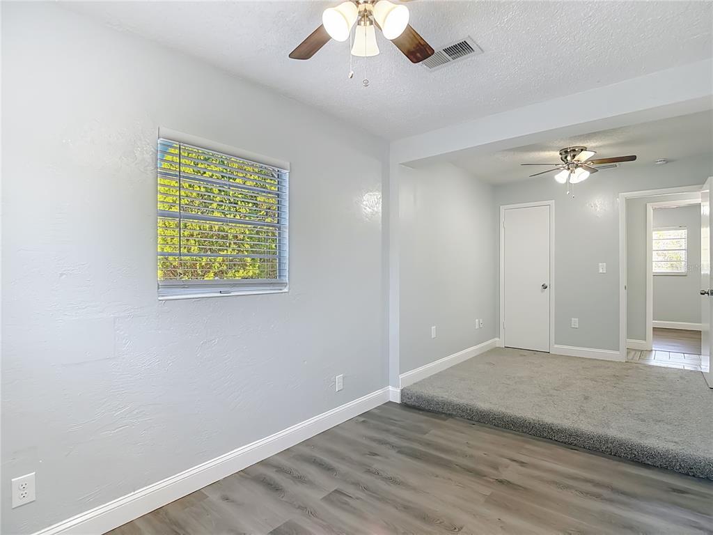 13156 Odham Street Spring Hill, FL 34609 - Photo 19 of 54 an empty room with a chandelier fan and wooden floor