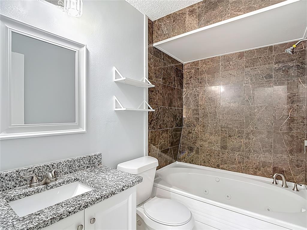 13156 Odham Street Spring Hill, FL 34609 - Photo 25 of 54 a bathroom with a granite countertop sink toilet and shower