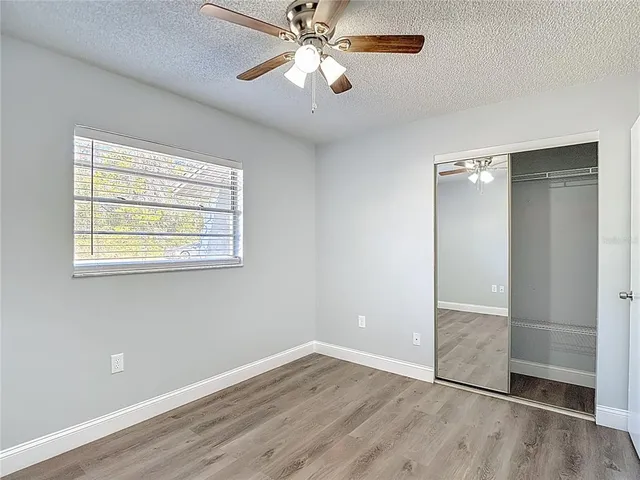 an empty room with wooden floor chandelier fan and windows