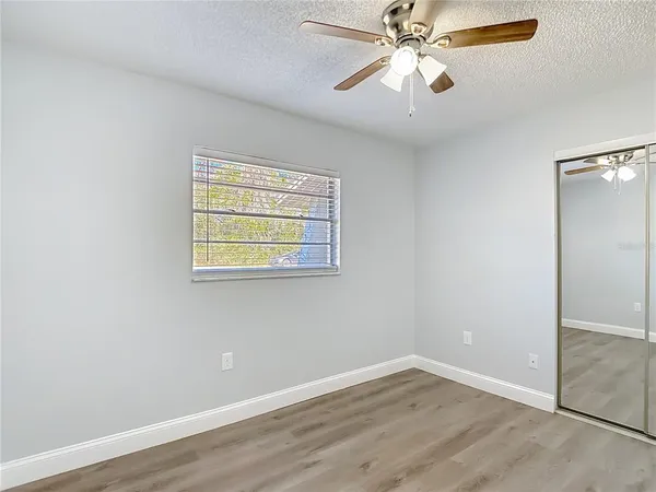 an empty room with wooden floor closet and ceiling fan