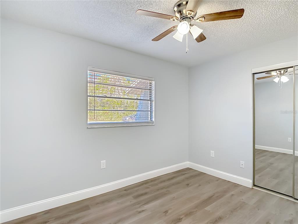 13156 Odham Street Spring Hill, FL 34609 - Photo 27 of 54 an empty room with wooden floor chandelier fan and windows