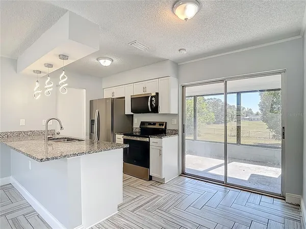 a kitchen with granite countertop a stove a sink and a refrigerator