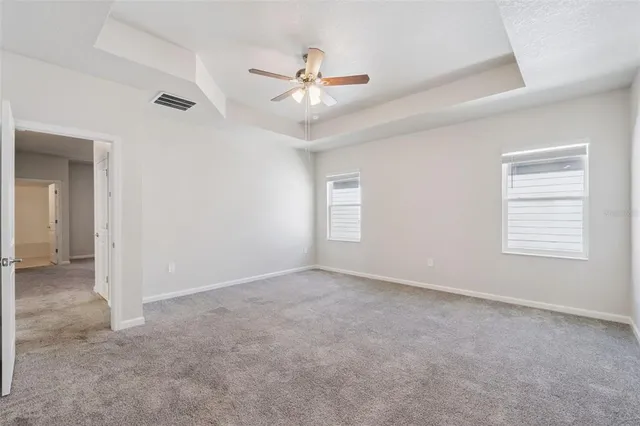 an empty room with windows and ceiling fan