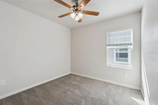 an empty room with a window and a fan