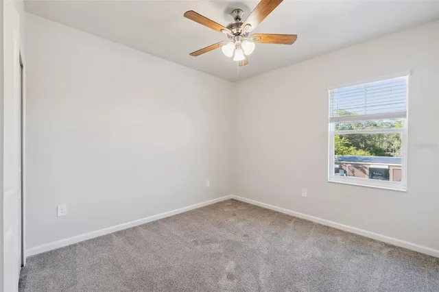 an empty room with a window and a fan