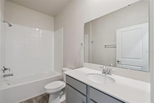 a bathroom with a granite countertop sink toilet mirror vanity and bathtub