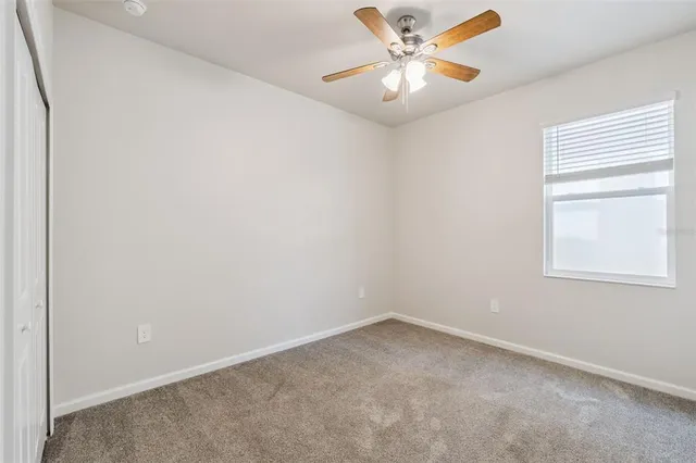 an empty room with a window and a fan