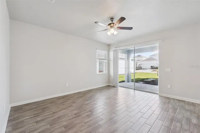 a view of an empty room with a window and wooden floor