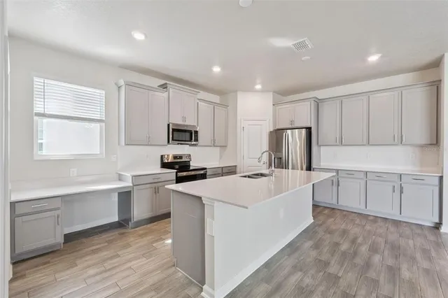 a large white kitchen with cabinets stove a sink and dishwasher
