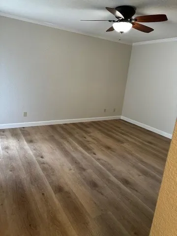 an empty room with wooden floor fan and windows