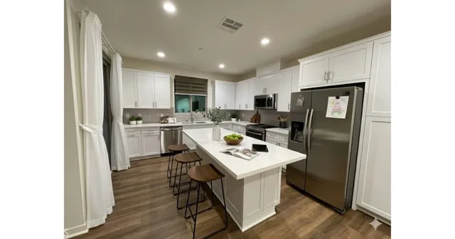a kitchen with stainless steel appliances a refrigerator a sink dishwasher and a stove with wooden floor