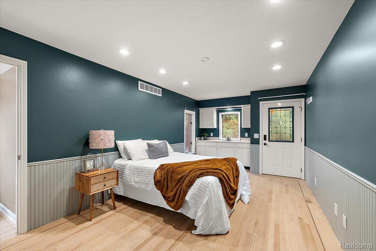 707 West Sutton Road Metamora, MI 48455 - Photo 49 of 84 Recessed ceiling lighting, wood-finish flooring, white paneling, white cabinetry, and a door with decorative glass