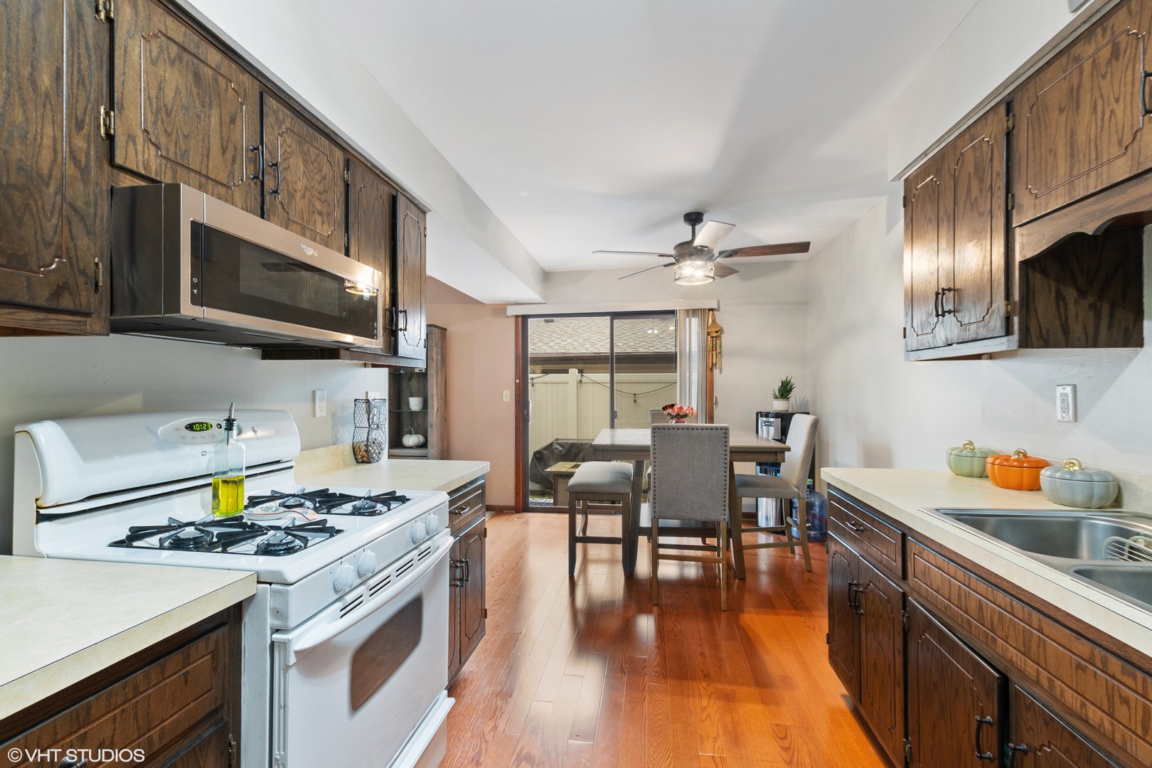 270 East Woodlawn Road, Unit 270 New Lenox, IL 60451 - Photo 5 of 14 a kitchen with stainless steel appliances granite countertop a stove top oven a sink a dining table and chairs with wooden floor