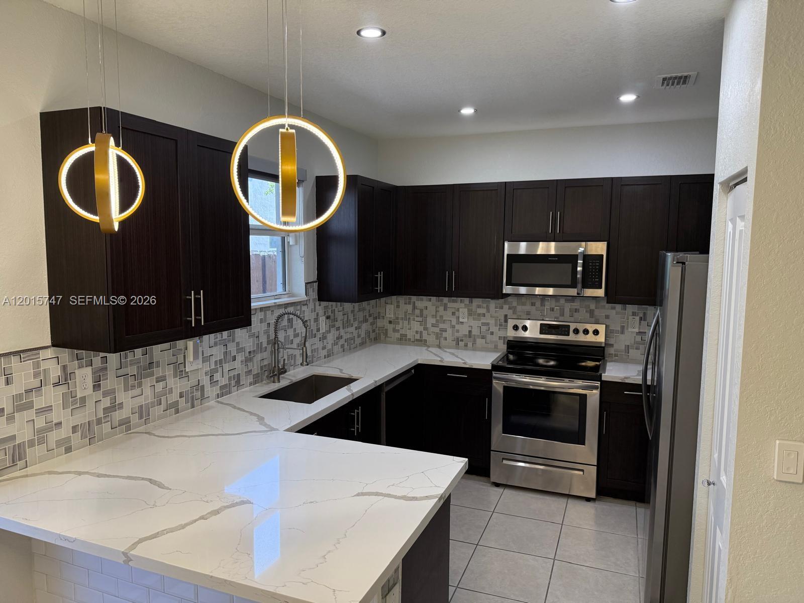 2614 Southeast 13th Street Homestead, FL 33035 - Photo 4 of 19 a kitchen with stainless steel appliances granite countertop a sink and a stove