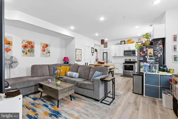 a living room with lots of furniture and kitchen view with wooden floor