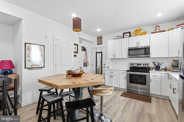 a kitchen with stainless steel appliances a stove a sink dishwasher a dining table and chairs with wooden floor