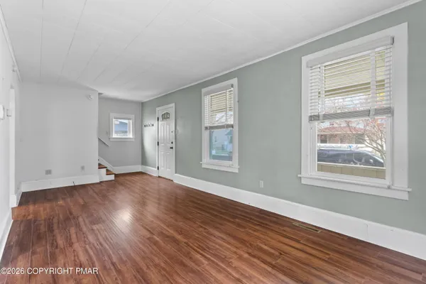 a view of an empty room with wooden floor and a window