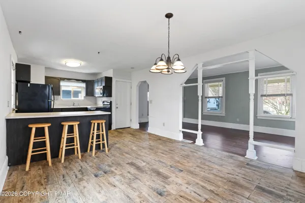 a view of a dining room and livingroom with furniture wooden floor a chandelier
