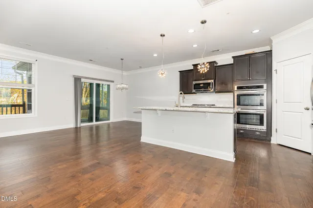 a room with stainless steel appliances kitchen island furniture and a chandelier