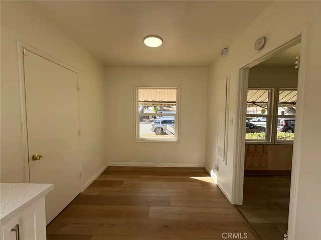 a view of an empty room with window and wooden floor