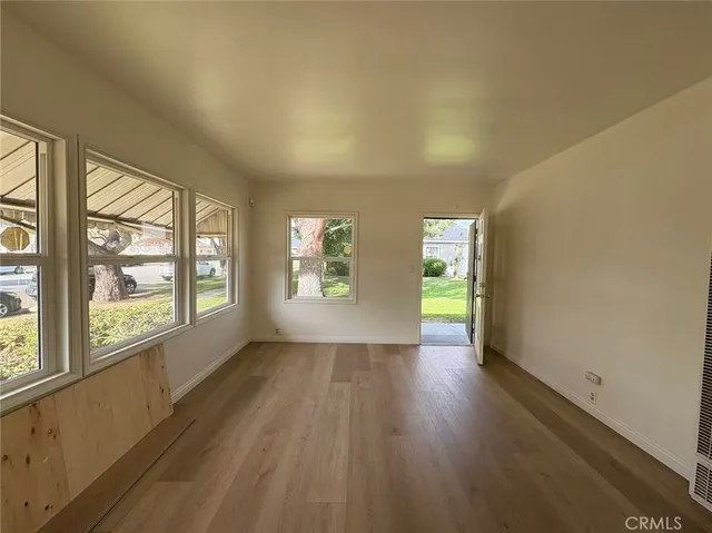 an empty room with wooden floor and windows