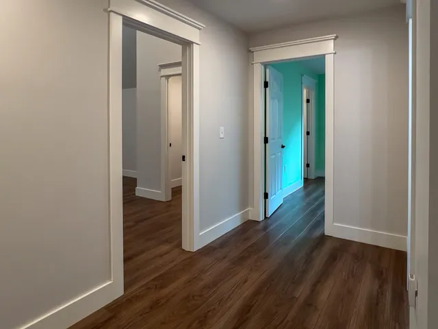 an empty room with wooden floor chandelier fan and windows
